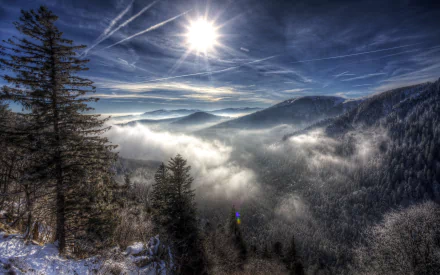 HD desktop wallpaper of a winter scene featuring sun rays piercing through mist over snow-covered mountains and forests.