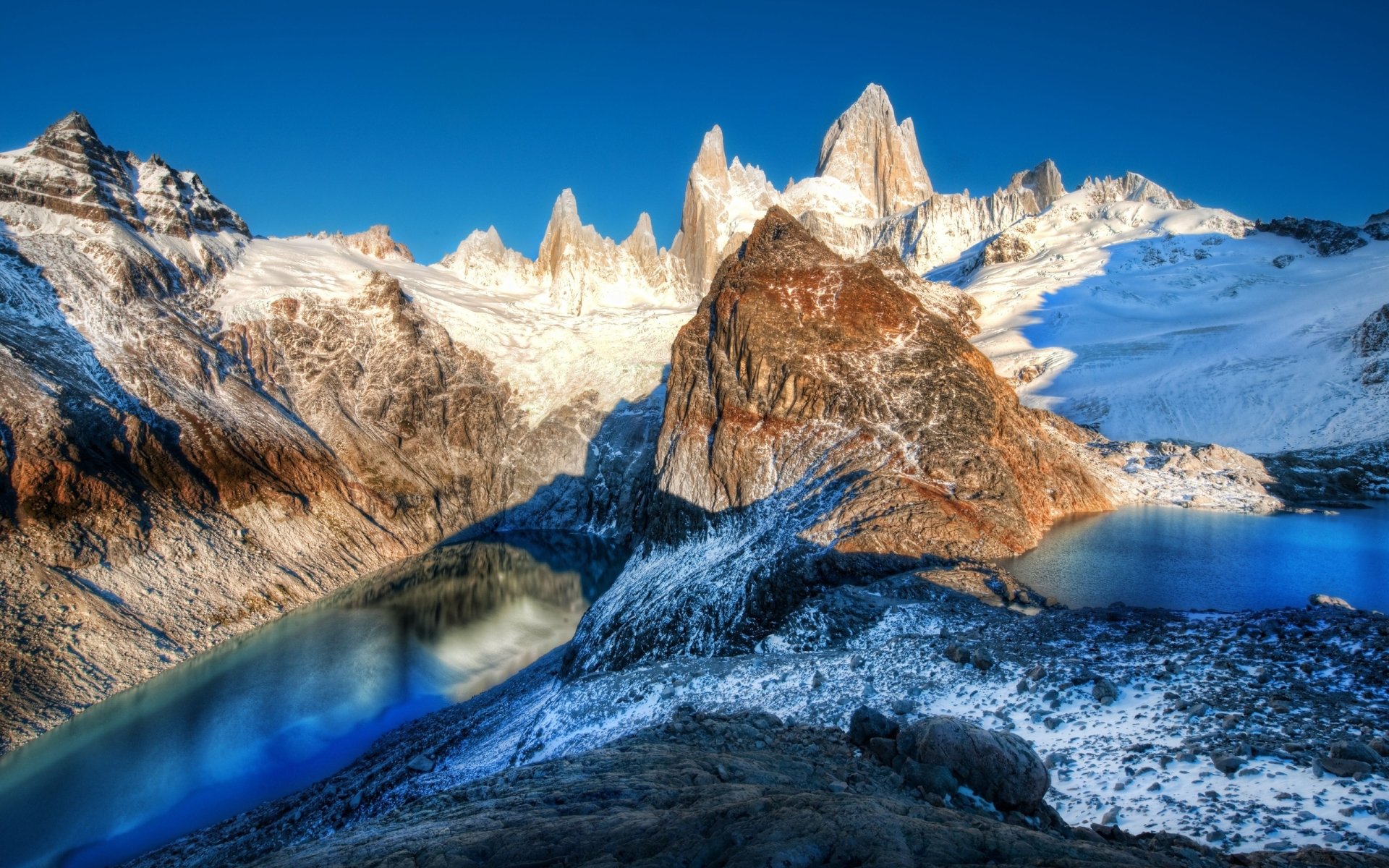 2K Quad HD PC desktop wallpaper and background: nature, mountain scene with jagged snow-covered peaks and rocky ridges mirrored in twin alpine lakes beneath a vivid blue sky.