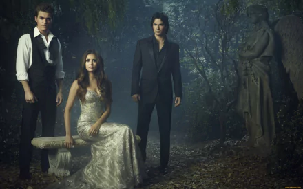 A moody scene from the TV show The Vampire Diaries features three main characters positioned in a mystical forest setting, creating a captivating HD wallpaper.
