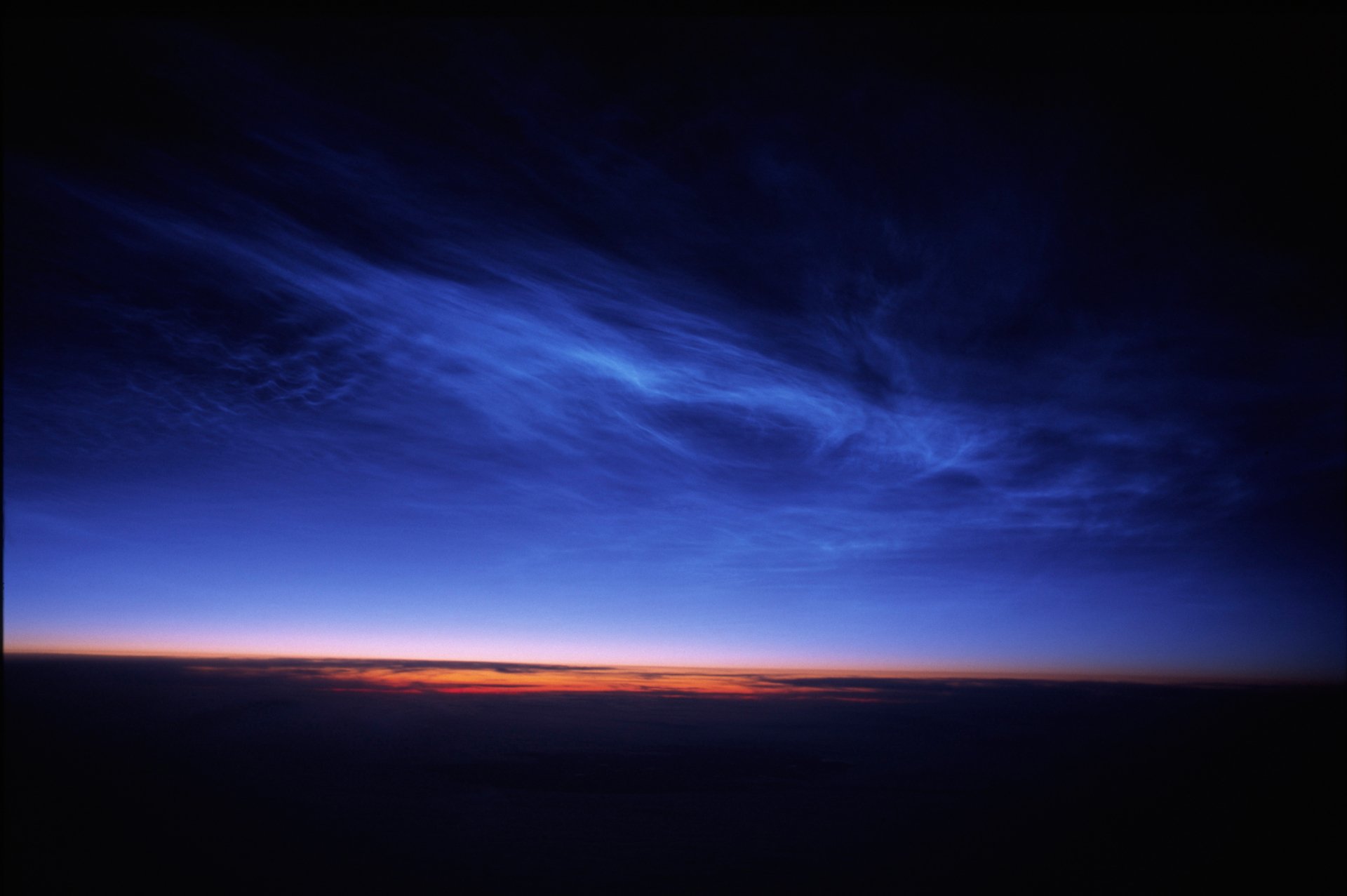 2K Quad HD PC desktop wallpaper/background: wide, deep-blue twilight sky with wispy clouds and a thin band of orange sunset glow along the horizon over a dark silhouette.