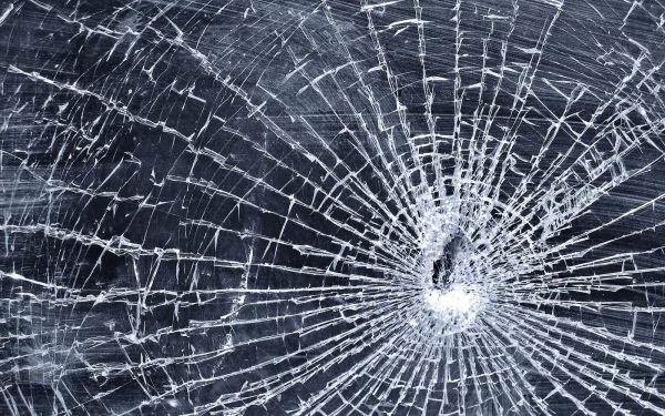 Abstract bullet hole in shattered glass with radiating cracks — HD PC desktop wallpaper and background.