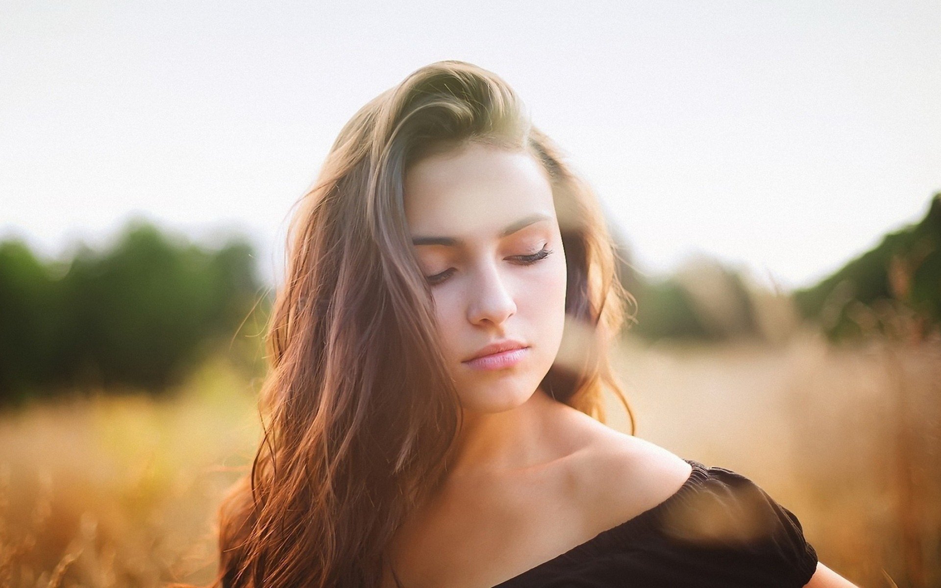 HD desktop wallpaper featuring a woman in a contemplative mood, standing amidst a golden field.