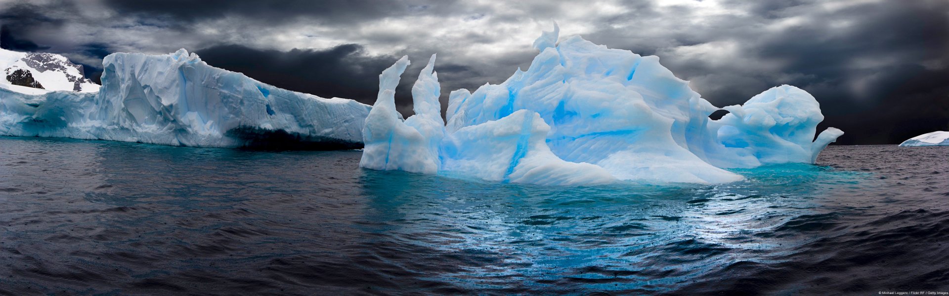HD PC desktop wallpaper showing a striking iceberg formation against a moody sky, highlighting nature’s icy beauty.