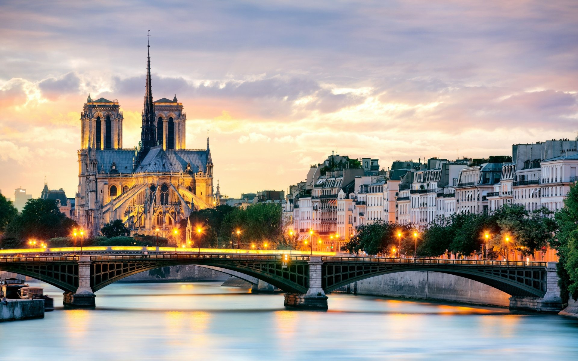 HD desktop wallpaper of Notre-Dame de Paris at sunset, showcasing the iconic religious landmark and surrounding Parisian architecture in France.
