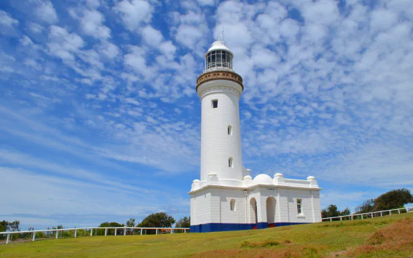 Norah Head Lighthouse stands tall under a partly cloudy sky on Australia’s coast, captured as a clear HD desktop wallpaper background.