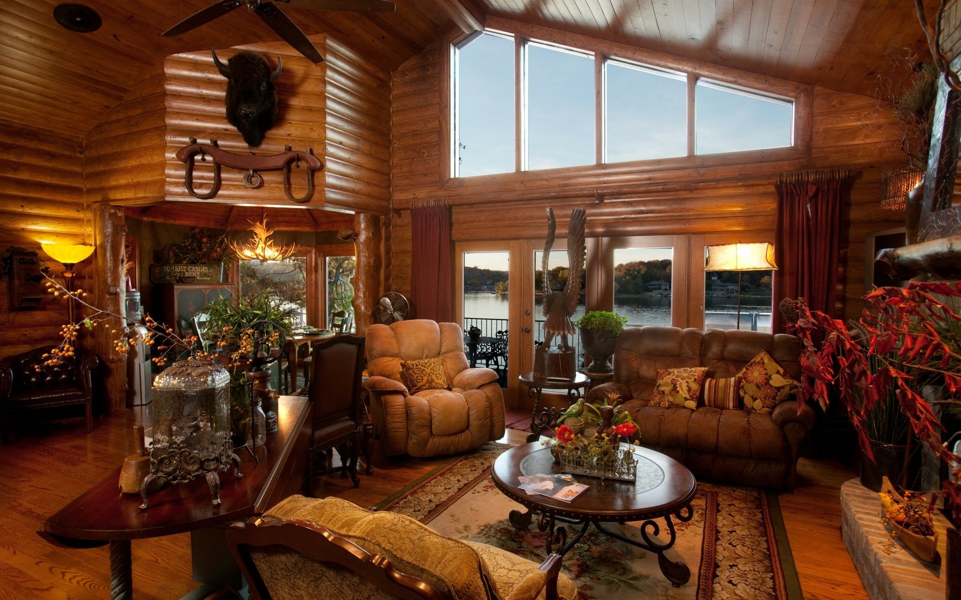 HD desktop wallpaper of a cozy room featuring a man-made wooden interior, a sofa set, armchairs, and large windows overlooking a scenic outdoor view.