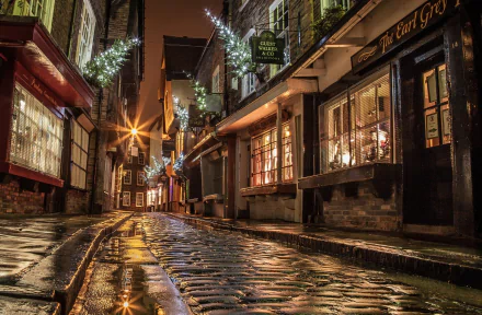 HD wallpaper and background featuring a festive cobblestone street adorned with Christmas lights, holiday decorations, and glowing store windows, evoking the spirit of Christmas.