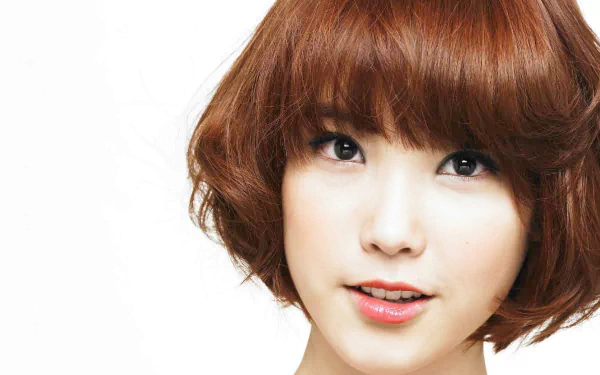 Close-up HD image of Korean singer IU with short brown hair, bright eyes, and a gentle smile, used as a PC desktop wallpaper background.