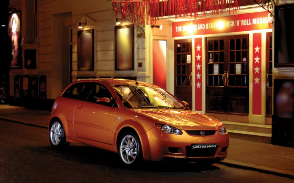 HD PC desktop wallpaper and background: orange Proton vehicle parked on a city street at night, reflecting theater marquee lights.
