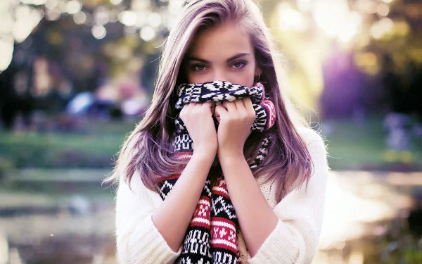 HD desktop wallpaper of a woman in a contemplative mood, wearing a sweater and scarf, with soft-focus natural background.