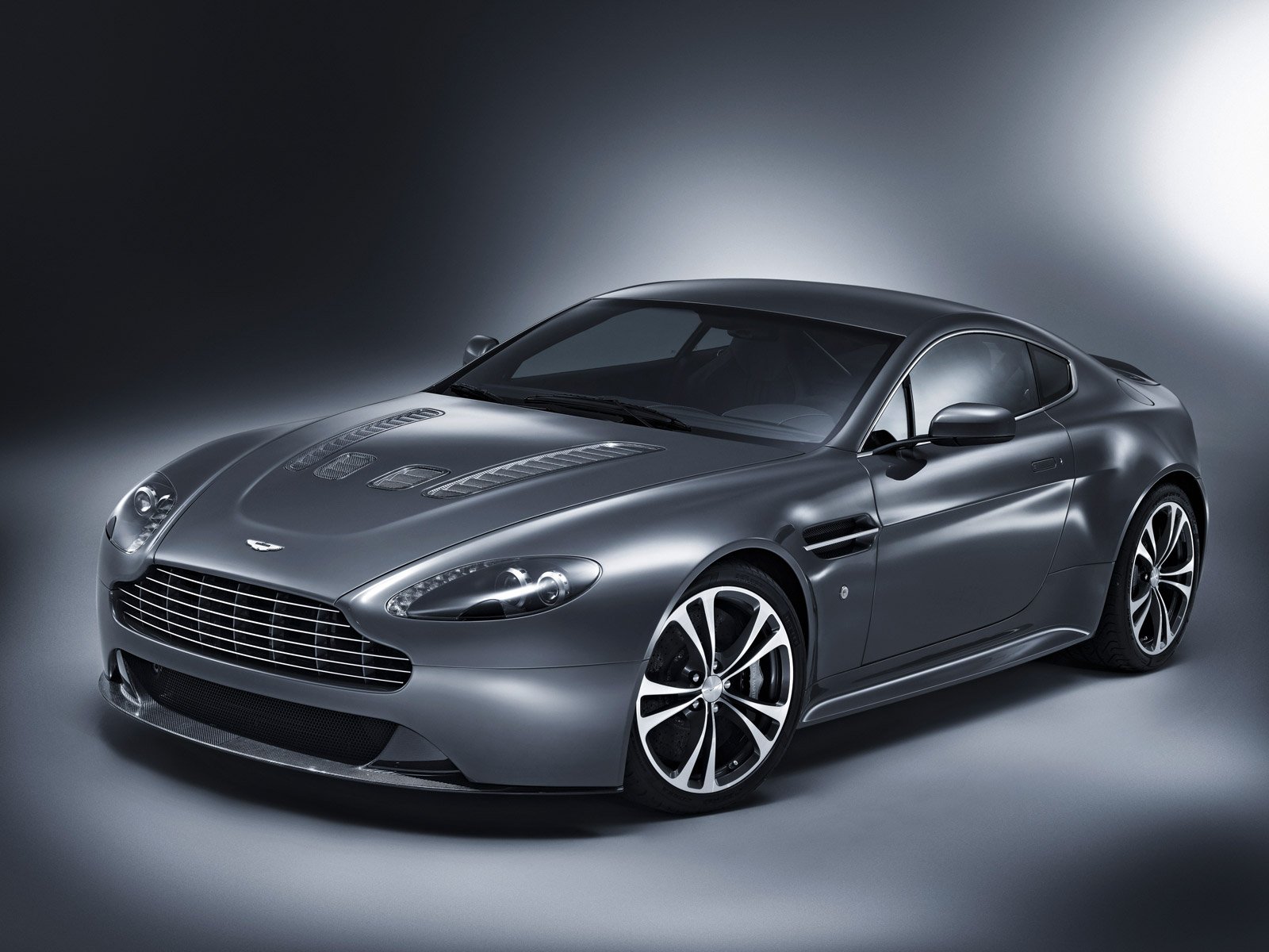 Silver Aston Martin V12 Vantage vehicle, three-quarter front view, presented as an HD PC desktop wallpaper/background on a soft gradient studio backdrop.