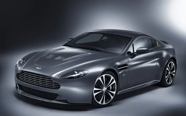 Silver Aston Martin V12 Vantage vehicle, three-quarter front view, presented as an HD PC desktop wallpaper/background on a soft gradient studio backdrop.