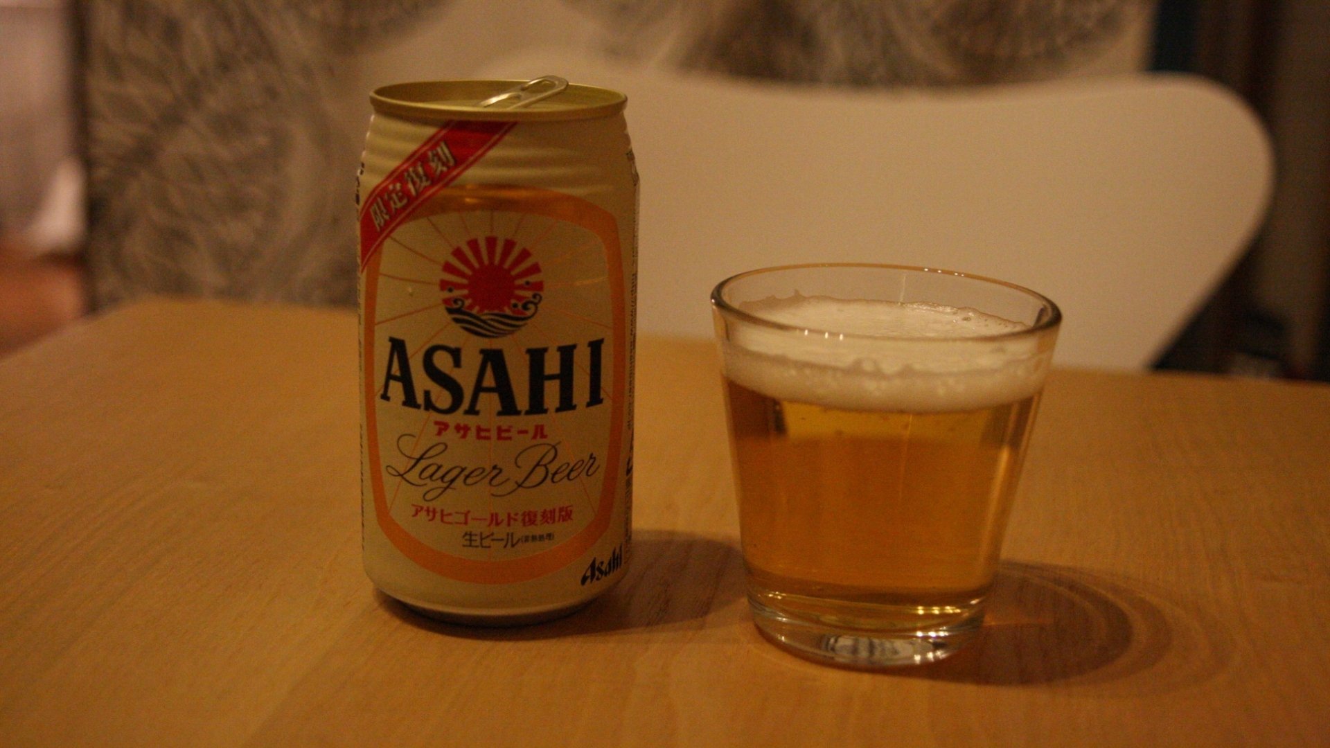 HD PC desktop wallpaper: Asahi beer can beside a poured glass on a wooden table with a warm indoor background — beer and food themed.