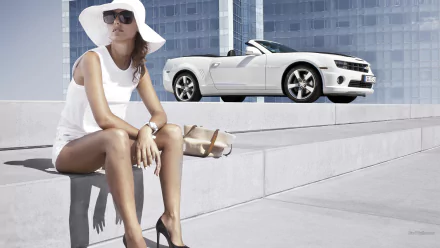A woman in a stylish white outfit and wide-brim hat sits on concrete steps with a white Chevrolet Camaro Convertible in the background, captured in an HD PC desktop wallpaper.