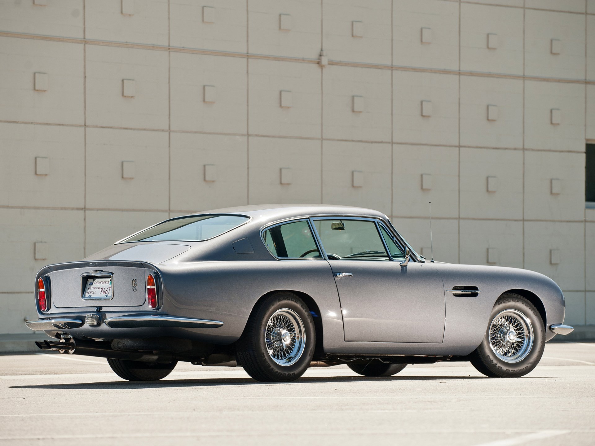 Silver Aston Martin DB6 classic vehicle parked before a tiled wall, rendered as an HD PC desktop wallpaper and background.
