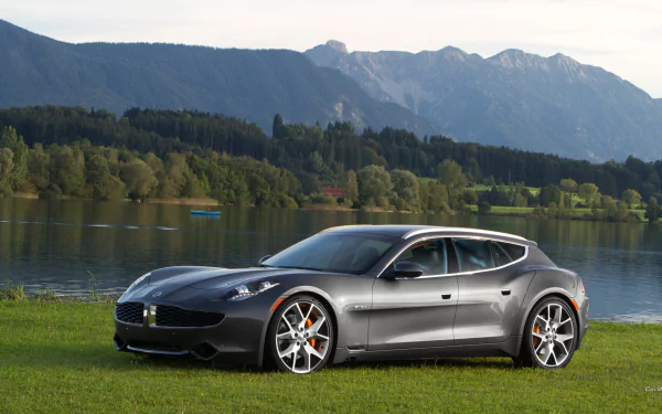 Gray Fisker Surf vehicle parked on a lakeside lawn with mountains beyond — HD PC desktop wallpaper and background.