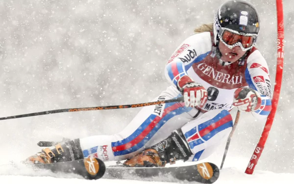 High-speed slalom skiing action: racer carving a turn through blowing snow around a gate, intense Sports scene rendered as a 2K Quad HD PC desktop wallpaper.