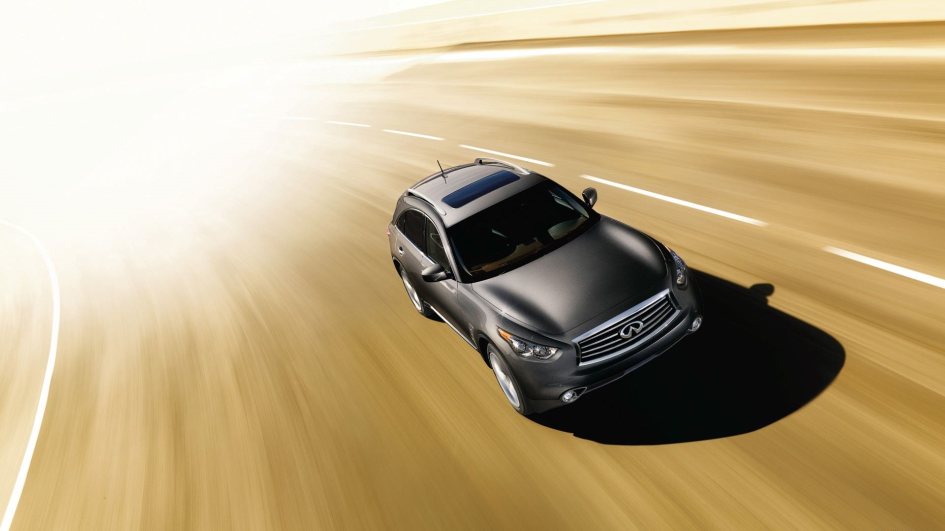 Sleek gray Infiniti QX70 racing down a sunlit highway with dramatic motion blur — HD PC desktop wallpaper and background.