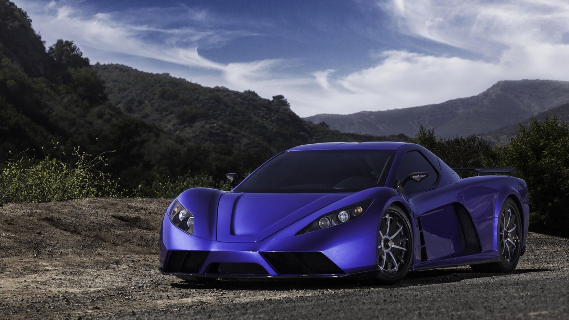 HD PC desktop wallpaper/background: sleek blue Kepler Motion sports vehicle parked on a mountain road beneath dramatic, sweeping clouds.