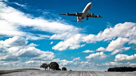 A Swiss Airlines passenger plane takes off against a vibrant blue sky, with fluffy clouds and a picturesque landscape below, making for a striking 4K Ultra HD desktop wallpaper.