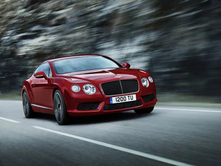 Red Bentley Continental GT V8 speeding on a mountainous road, captured in a sharp HD PC desktop wallpaper and background.