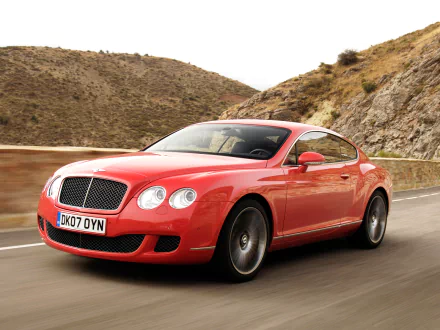 HD desktop wallpaper featuring a red Bentley Continental GT Speed cruising on a winding mountain road.