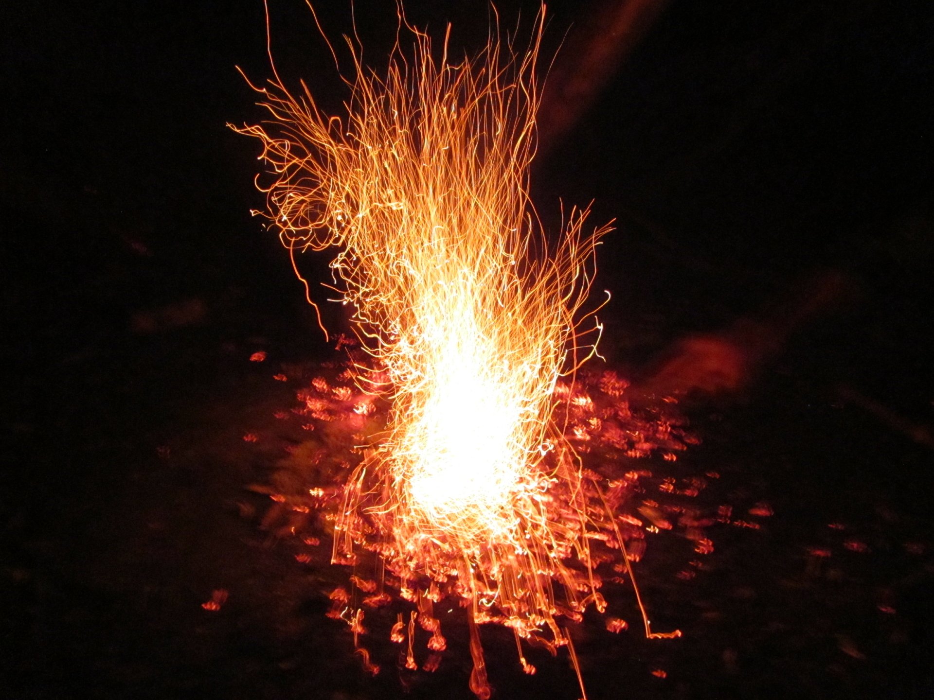 4K Ultra HD fire photograph: a column of flames and orange sparks bursting from glowing embers on a black background — PC desktop wallpaper.