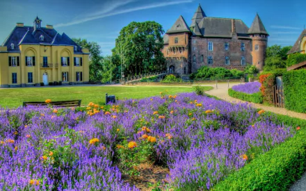 HD wallpaper of a scenic view featuring a stately house with a vibrant garden of purple and orange flowers in the foreground.
