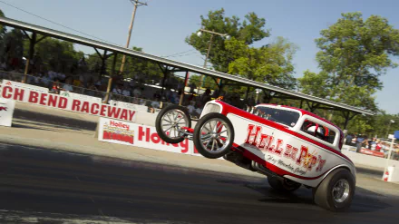 4K Ultra HD PC desktop wallpaper of a vintage hot rod vehicle popping a wheelie on a drag strip, crowd-filled grandstand and trees blurred in the sunny background.