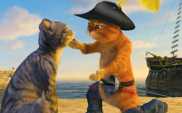 A vibrant HD desktop wallpaper featuring Puss in Boots, an orange cat in a pirate hat, playfully interacting with a gray tabby on a scenic beach with a ship in the background.