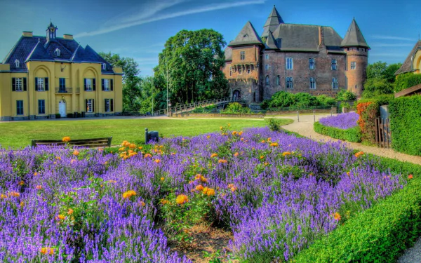 HD wallpaper of a scenic view featuring a stately house with a vibrant garden of purple and orange flowers in the foreground.