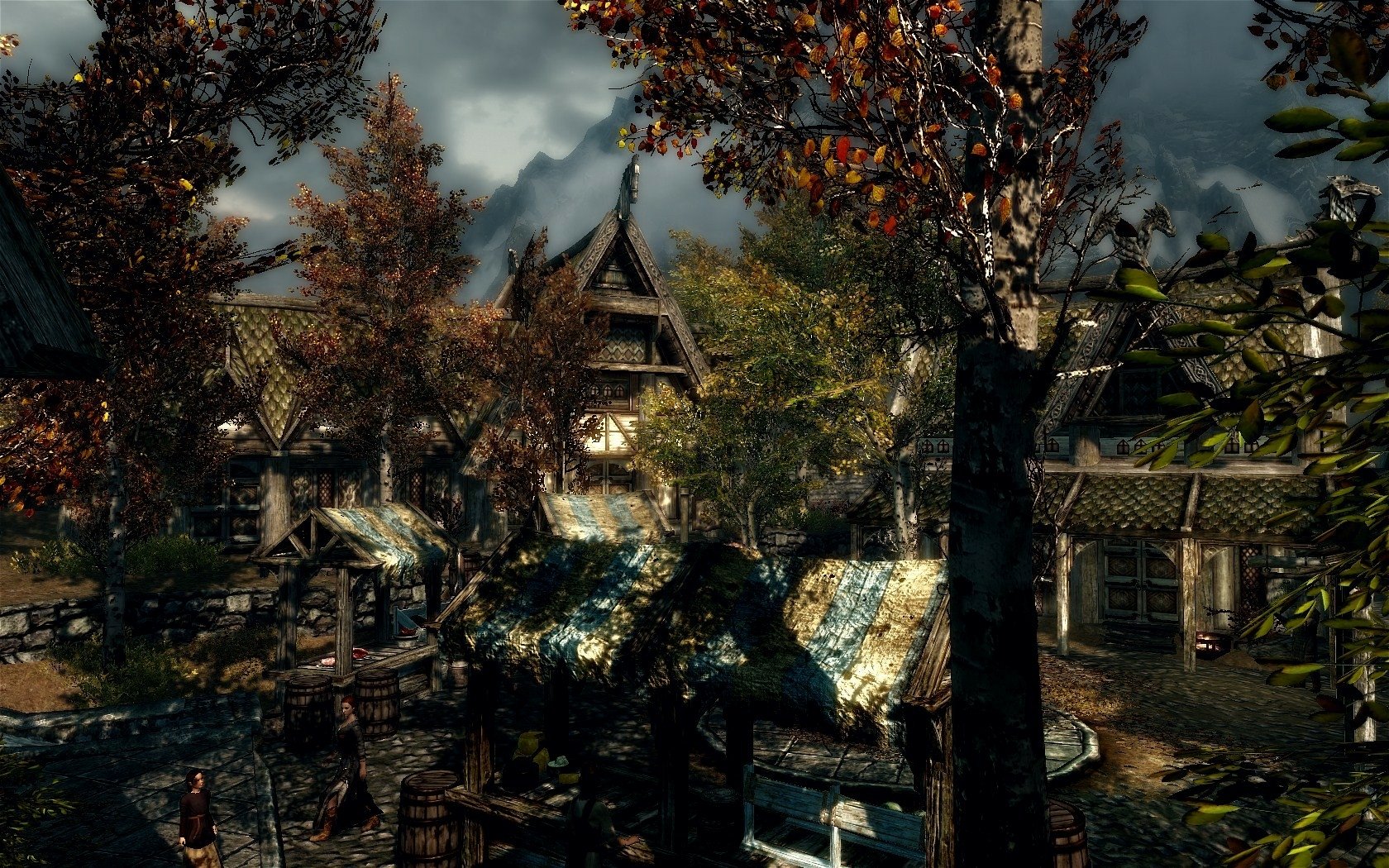 HD PC desktop wallpaper from the video game The Elder Scrolls V: Skyrim, featuring a detailed autumn village scene with houses and trees under a cloudy sky.