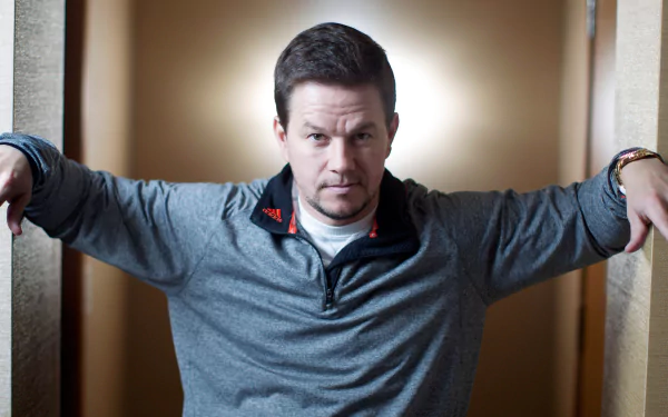 Unidentified man in a grey pullover leaning between a doorway with arms outstretched, intense gaze; 4K Ultra HD PC desktop wallpaper/background.