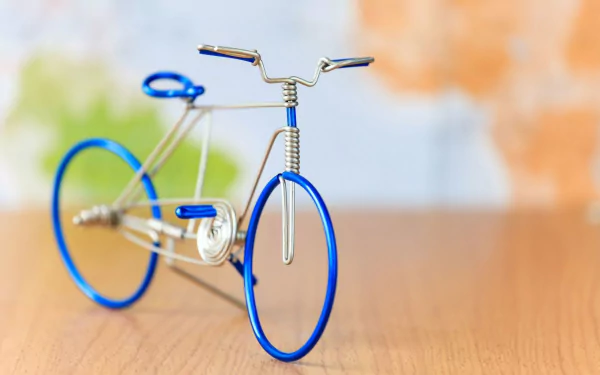 A close-up of a decorative bicycle model, crafted with blue wire, set against a soft, colorful background. This image serves as an HD desktop wallpaper and background.