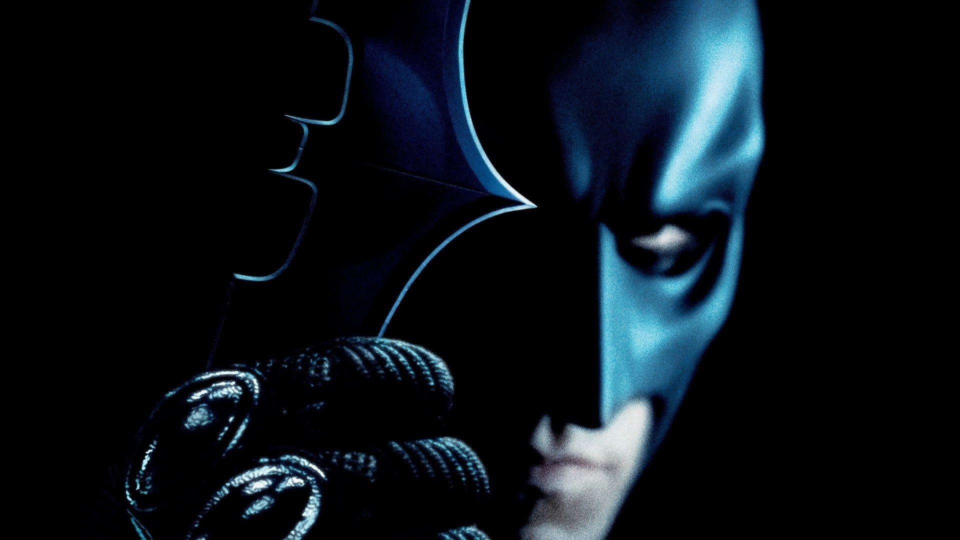 A dramatic HD wallpaper featuring Batman from the movie The Dark Knight, capturing the iconic character in a dark atmosphere with a focus on his mask and gloves.