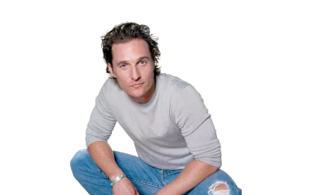 HD desktop wallpaper of American actor and celebrity Matthew McConaughey wearing a light gray shirt and ripped blue jeans, seated against a white background.