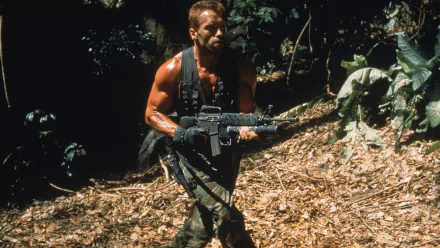 A muscular soldier armed with a rifle navigates a dense jungle, embodying the action and intensity of the movie Predator. This high-definition wallpaper adds cinematic flair to any desktop.