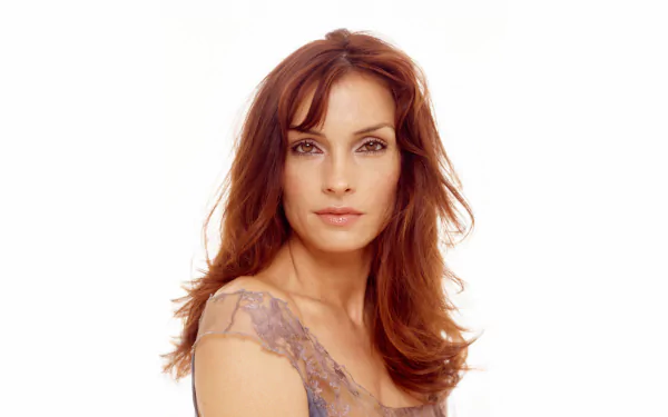A stunning HD wallpaper featuring Dutch actress Famke Janssen, showcasing her captivating beauty with soft, flowing hair and a serene expression against a simple background.