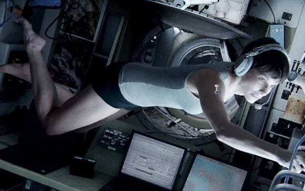 A striking HD wallpaper from the movie Gravity (2013), featuring a floating astronaut in a spacecraft, immersed in a moment of intense concentration amidst advanced technology.