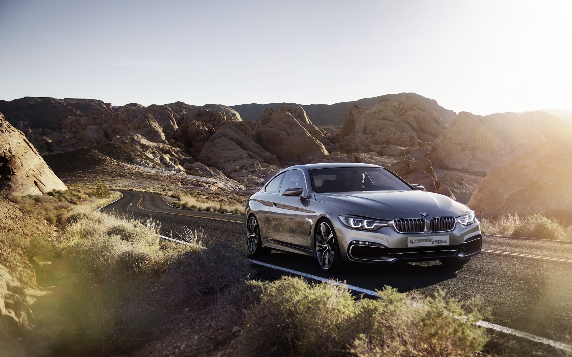 A sleek BMW Concept 4 Series Coupé parked on a rocky desert road, captured in this HD PC desktop wallpaper showcasing the vehicle’s elegant design.