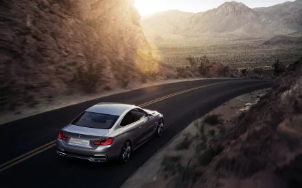 Silver BMW Concept 4 Series Coupé vehicle driving along a winding desert mountain road at sunset — 2K Quad HD PC desktop wallpaper background