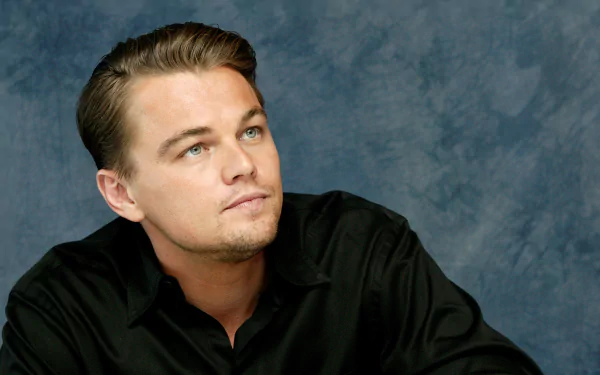 Portrait of American actor Leonardo DiCaprio against a textured blue background, captured in high resolution for use as a desktop wallpaper.