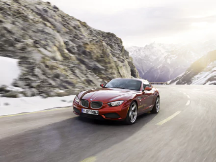 HD desktop wallpaper featuring a red BMW Zagato Coupe driving on a mountain road with rocky cliffs and snow-covered peaks in the background.