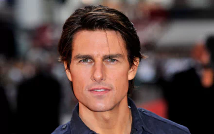 A high-definition desktop wallpaper featuring American actor Tom Cruise, showcasing his confident expression and classic style amidst a blurred background of an event.