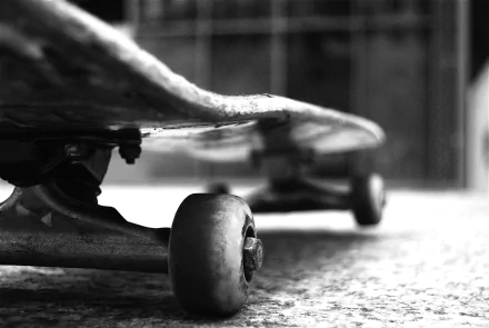 A low-angle view of a skateboard on the ground, capturing the details of the wheels and deck. This 4K Ultra HD wallpaper showcases the essence of skateboarding and sports.