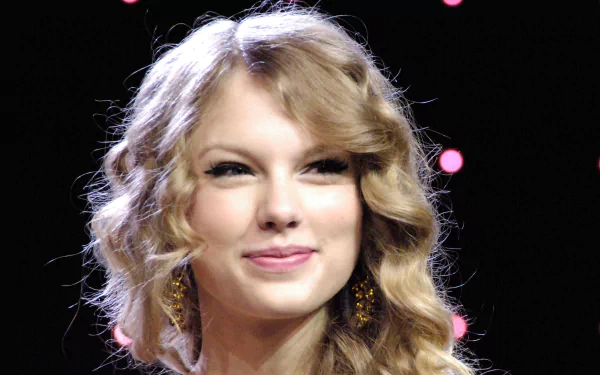 HD desktop wallpaper featuring a close-up of Taylor Swift with wavy blonde hair and earrings, set against a dark background with soft pink lights, highlighting music themes.