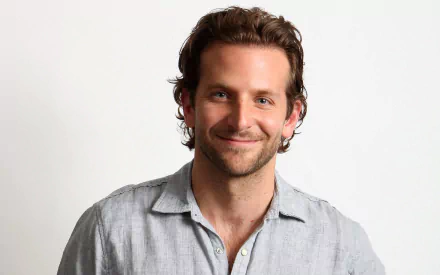 HD desktop wallpaper featuring American actor and celebrity Bradley Cooper smiling against a plain white background.