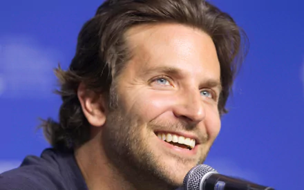 HD PC desktop wallpaper featuring American actor and celebrity Bradley Cooper smiling during a public appearance.