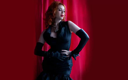HD desktop wallpaper of American actress and celebrity Christina Hendricks posing elegantly in black against a vibrant red curtain background.