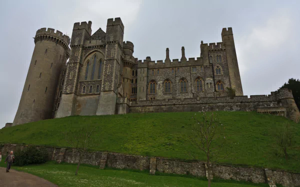 HD PC desktop wallpaper of Arundel Castle: imposing man-made medieval stone fortress on a grassy mound beneath a cloudy sky.
